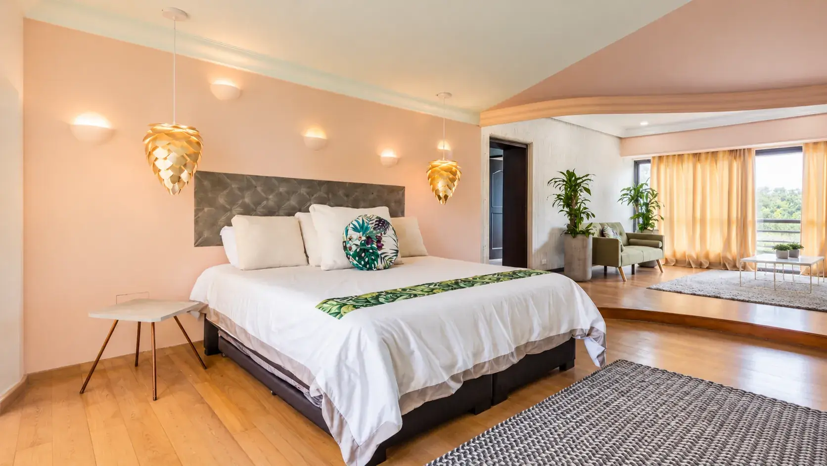 Suite principal panorámica en tonos tropicales con lámparas colgantes doradas, diseño de ALUZINA en Medellín